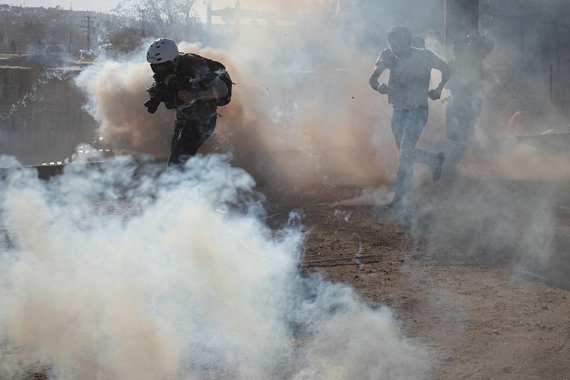 US border agents fire tear gas as some migrants protesting slow asylum process try to breach fence