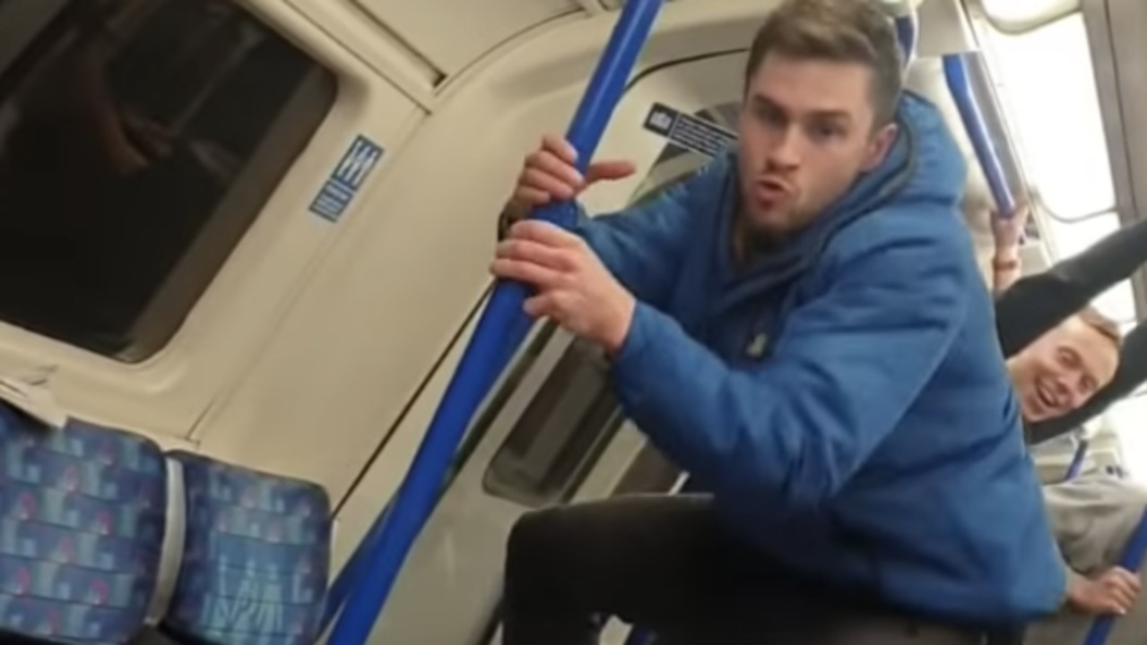 White man on tube directs monkey impression and noises at a black passenger